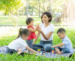 bella giovane mamma asiatica e figlia che giocano a blocchi giocattolo per lo sviluppo dell'apprendimento felice e divertente al parco in estate, madre e bambino allegra attività insieme al giardino in vacanza, concetto di famiglia. foto