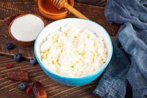 ricotta con miele e frutti di bosco su fondo di legno. colazione vegetariana leggera. foto