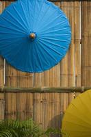 parte di ombrelli di carta blu e gialli appesi su sfondo muro di legno di bambù in stile vintage e cornice verticale foto
