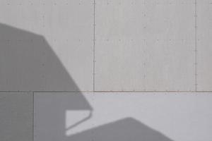 luce solare e ombra della struttura della casa sulla superficie grigia della parete di gesso foto