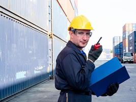 caposquadra ingegnere dirigente europa giallo cappello nero ombra sicurezza parlare telefono sguardo lavoro rapporto magazzino terminale container import export affari azienda sito cliente logistica globale internazionale foto