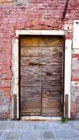 antica porta di legno e vecchio muro di mattoni a venezia, italia foto