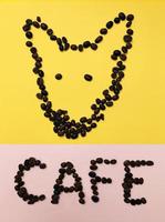 primo piano cane caffè contorno chicchi di caffè tostati colore marrone su sfondo giallo e rosa pastello segnaletica caffetteria foto