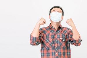 passato il concetto di cattiva situazione, uomo asiatico che indossa una maschera protettiva in azione di gioia, vittoria o molto felice isolato su grigio foto