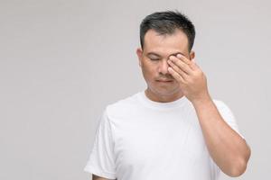 concetto di irritazione agli occhi, ritratto di un uomo asiatico in postura di occhi stanchi, irritazione o problemi agli occhi. girato in studio isolato su grigio foto