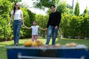 le attività per le vacanze in famiglia includono padre, madre e figli con barbecue da campeggio e giocare in cortile insieme felicemente in vacanza. foto