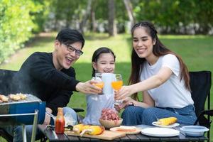 le attività per le vacanze in famiglia includono padre, madre e figli con barbecue da campeggio e giocare in cortile insieme felicemente in vacanza. foto