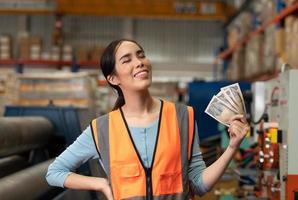 ritratto di una donna asiatica con le emozioni che sorgono con i soldi ricevuti come salario lavorando in magazzino. foto