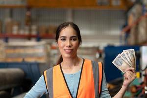 ritratto di una donna asiatica con le emozioni che sorgono con i soldi ricevuti come salario lavorando in magazzino. foto