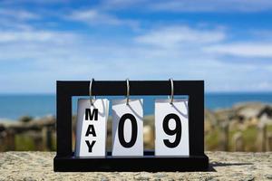 09 maggio testo della data del calendario su telaio in legno con sfondo sfocato dell'oceano. foto