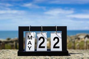 22 maggio testo della data del calendario su telaio in legno con sfondo sfocato dell'oceano. foto