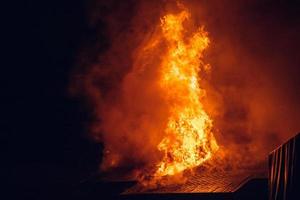 casa in fiamme di notte. temi di incendi dolosi, disastri ed eventi estremi. foto