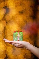 buon Natale e Felice Anno nuovo. confezione regalo nelle mani di una donna con bokeh incandescente. foto