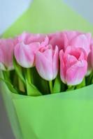 bouquet di fiori di tulipani con tulipani rosa in carta verde foto