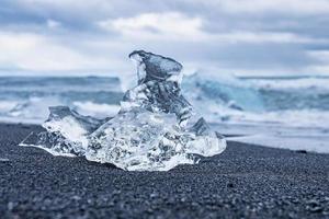 primo piano di un bel pezzo di iceberg sulla sabbia nera della spiaggia di diamanti contro il cielo foto