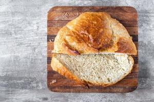 pagnotta di pane a fette con bei picchi di crosta su blocco da macellaio foto