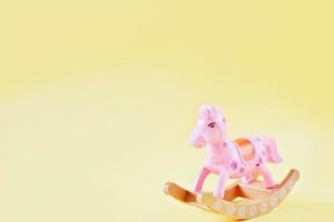 cavallo a dondolo giocattolo per bambini. piccolo cavallo rosa su sfondo giallo. regalo per bambini in età prescolare. sviluppo dell'intelligenza emotiva. copia spazio per il testo foto