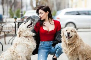 ragazza che cammina in città con i suoi cani. donna che gioca con un cane bianco. cane che si abbraccia foto