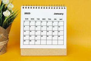 calendario bianco gennaio 2023 con pianta in vaso su sfondo giallo. foto