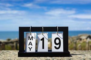 19 maggio testo della data del calendario su telaio in legno con sfondo sfocato dell'oceano. foto