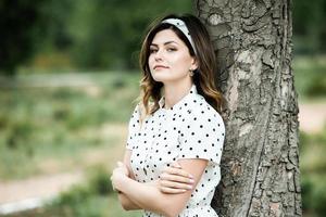 ritratto di donna con i capelli mossi dal vento. ritratto di giovane bella ragazza bruna russa al parco verde estivo. donna bianca europea in abito. foto