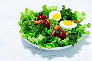 gustosa insalata di verdure miste fresche su piatto bianco e piatto di legno. foto
