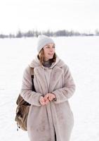 giovane ragazza in abiti beige, pelliccia fatta di pelliccia artificiale cammina in inverno foto