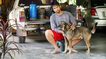 l'uomo asiatico si siede con un cane nella sua casa foto