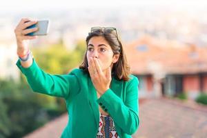 la giovane bella ragazza che prende manda un bacio via selfie con il cellulare foto