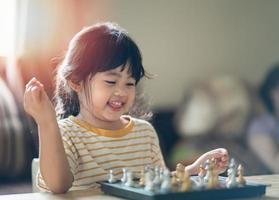 piccolo bambino asiatico che gioca a scacchi nel soggiorno di casa.bambini intelligenti kid.fashion. piccolo genio bambino. gioco intelligente.scacchiera. concetto di attività del bambino. foto