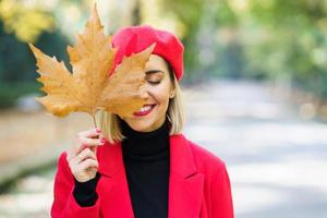 donna sorridente che copre il viso con foglia secca foto