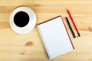 penna e tazza di caffè del taccuino in tavola di legno