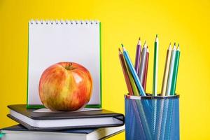 torna al concetto di scuola. materiale scolastico e libri su sfondo giallo. posto per il testo. foto