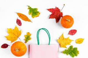 concetto di vendita autunnale. banner di sconto. shopping bag di carta e foglie cadute colorate su sfondo bianco. foto