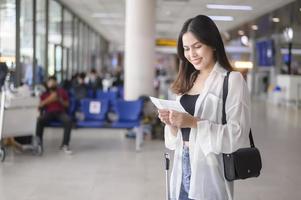 giovane viaggiatore femminile che trasporta valigie all'aeroporto internazionale, viaggi, vacanze e concetto di viaggio. foto