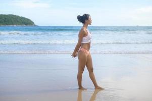 giovane donna asiatica in bikini che fa yoga sul concetto di spiaggia, salute e meditazione foto