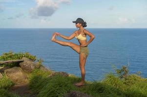 bella donna asiatica in abbigliamento sportivo che fa yoga sul picco di montagna del mare dopo il concetto di trekking, viaggio e meditazione. foto