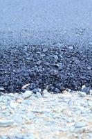 il manto stradale in asfalto in costruzione ha giunti di ghiaia, con uno sfondo nero e grigio come immagine verticale e orizzontale. foto