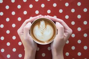 mani di donna che tengono latte art, tazza di caffè. foto