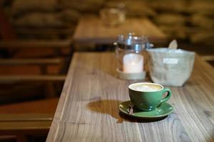latte caldo d'arte nella tazza verde sul tavolo di legno foto