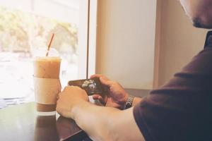 l'uomo sta usando il telefono cellulare mentre è seduto in una caffetteria foto