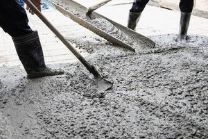 operaio che fa il lavoro di colata di calcestruzzo del pavimento in cantiere foto