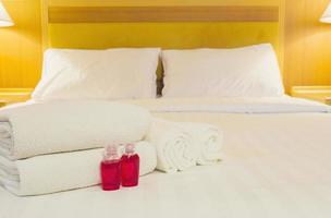 asciugamano dell'hotel con bottiglia di shampoo e sapone impostato sul letto bianco foto