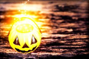 foto di tono scuro con faccia di zucca di halloween con caldo punto dorato evaporare sopra il secchio sopra la vecchia struttura in legno