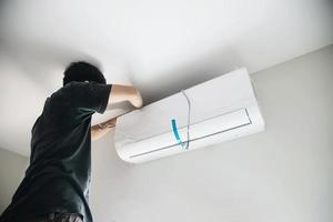 il tecnico sta installando il condizionatore d'aria durante la stagione calda foto