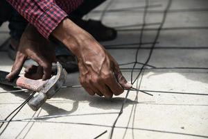 l'operaio edile sta legando l'acciaio strutturale, la preparazione del getto di calcestruzzo del pavimento foto