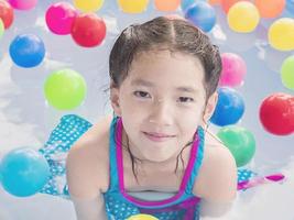 il bambino asiatico sta giocando in una piscina d'acqua per bambini con palline colorate foto