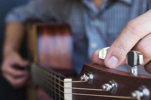 uomo che accorda la chitarra acustica foto