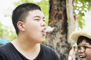 ragazzo asiatico che mangia felicemente fumante astuto - persone e spuntino concetto di tempo felice foto