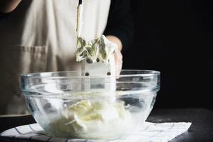 signora che fa la torta mettendo la crema con la spatola - concetto di cucina da forno fatto in casa foto